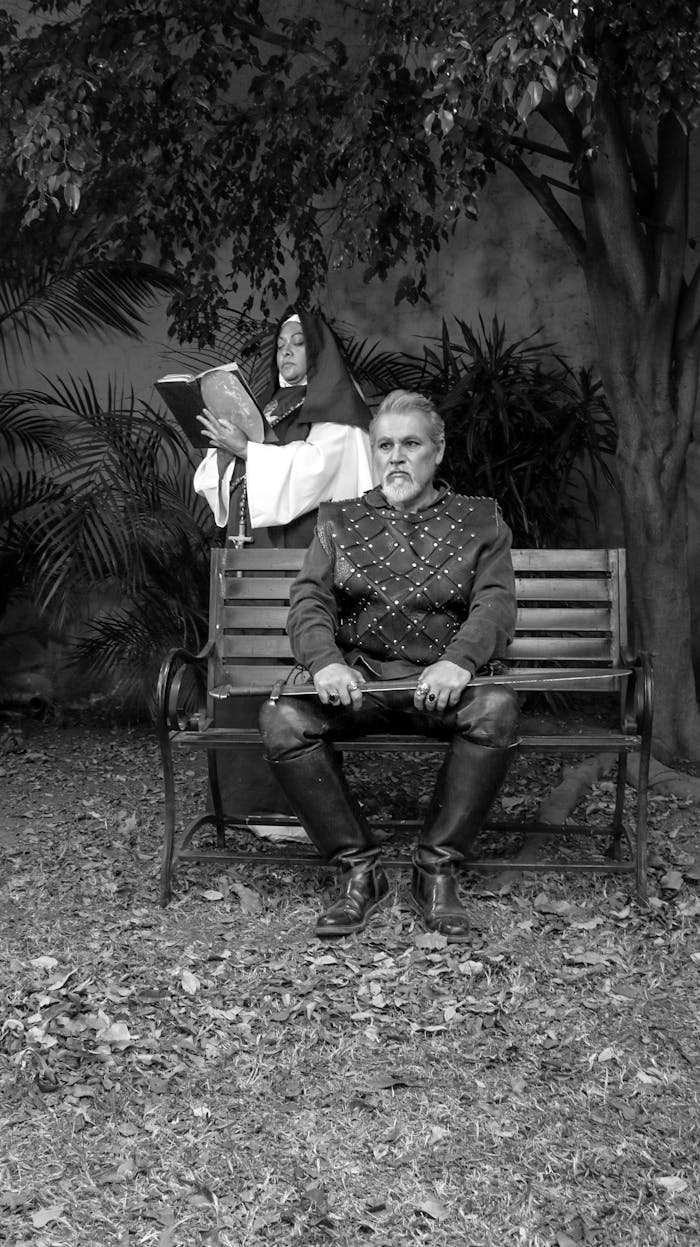 about-us-02 Medieval themed grayscale photo of a knight and nun in a garden setting.